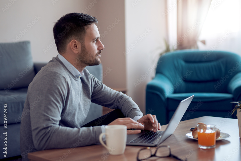Obraz na plátně Man sitting on floor while watching  laptop at home