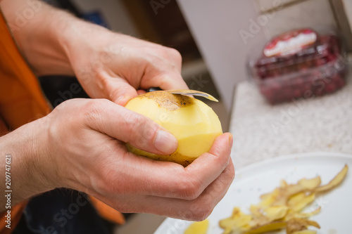 man peels with knife potatoes