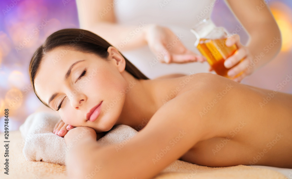 wellness, spa and beauty concept - close up of beautiful woman having massage over holidays lights background wellness, spa and beauty concept - close up of beautiful woman having massage over holidays lights background