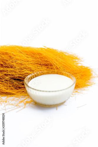 Close up of Raw vermicelli or sevee or seviyan or seviyaan isolated on white with a bowl of milk used to make kheer. photo