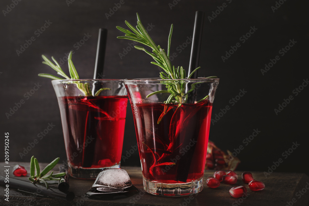 Fresh pomegranate drink with rosemary on black wooden background. Copy space.