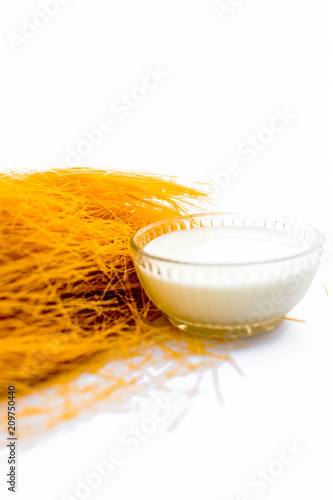 Close up of Raw vermicelli or sevee or seviyan or seviyaan isolated on white with a bowl of milk used to make kheer. photo