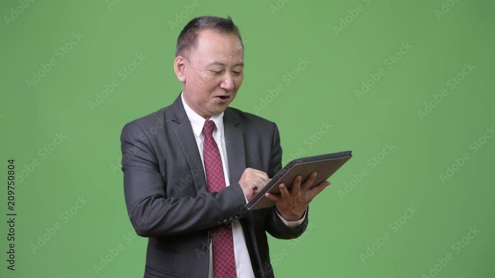 Mature Japanese businessman working with digital tablet Mature Japanese businessman working with digital tablet