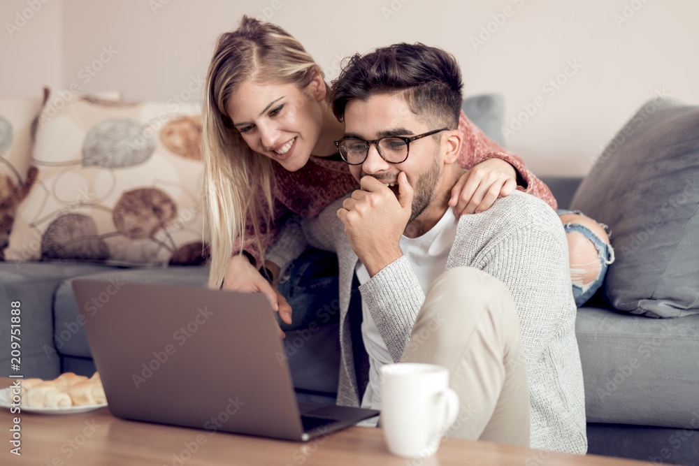 Attractive couple using laptop in the living room Attractive couple using laptop in the living room