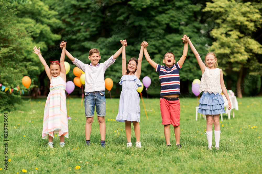 holidays, childhood and celebration concept - happy kids having fun on birthday party at summer park