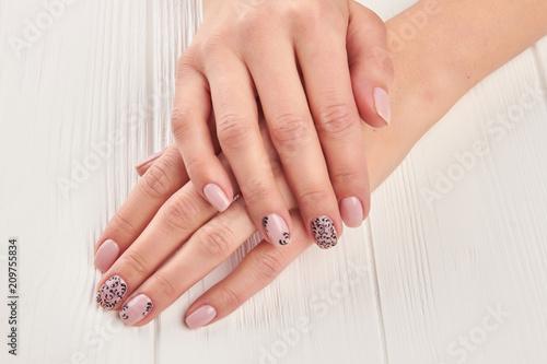Female hands with gentle manicure. Woman hands with beautiful nails design on white wooden background. Salon beauty and spa.