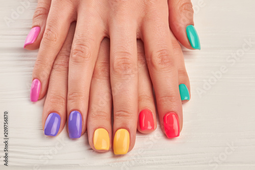 Young woman hands with colorful nails. Colorful nail polish on well-groomed woman hands close up. Nail treatment and spa. photo