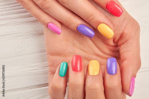 Woman hands with multicolored nail polish. Close up of female hands with beautiful summer manicure. Concept of nail treatment and spa.