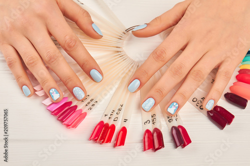 Manicured hands and nails color palette. Gentle winter manicure and hand-pinted nail samples. Variants of nails design on artificial nail samples. Beautiful winter manicure.