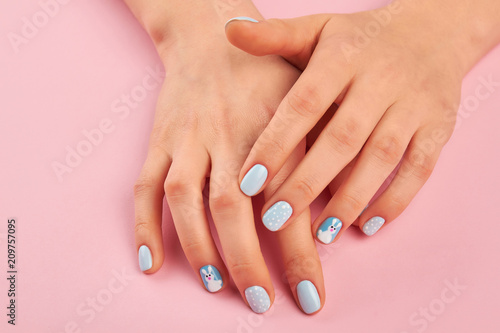 Trendy winter design manicure. Woman hands with cute winter design manicure on pink background. Nail art fashion style.