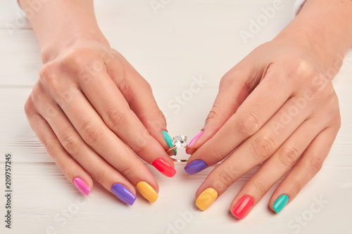 Manicured hands holding ring with diamond. Female hands with summer manicure holding golden ring with precious stone. Perfect summer nail design.