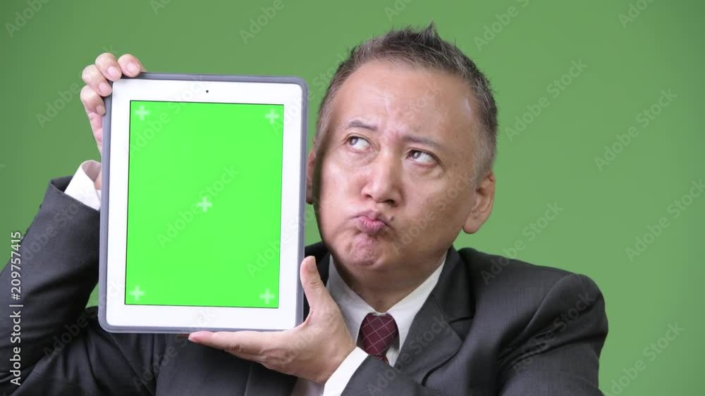 Mature Japanese businessman showing digital tablet Mature Japanese businessman showing digital tablet