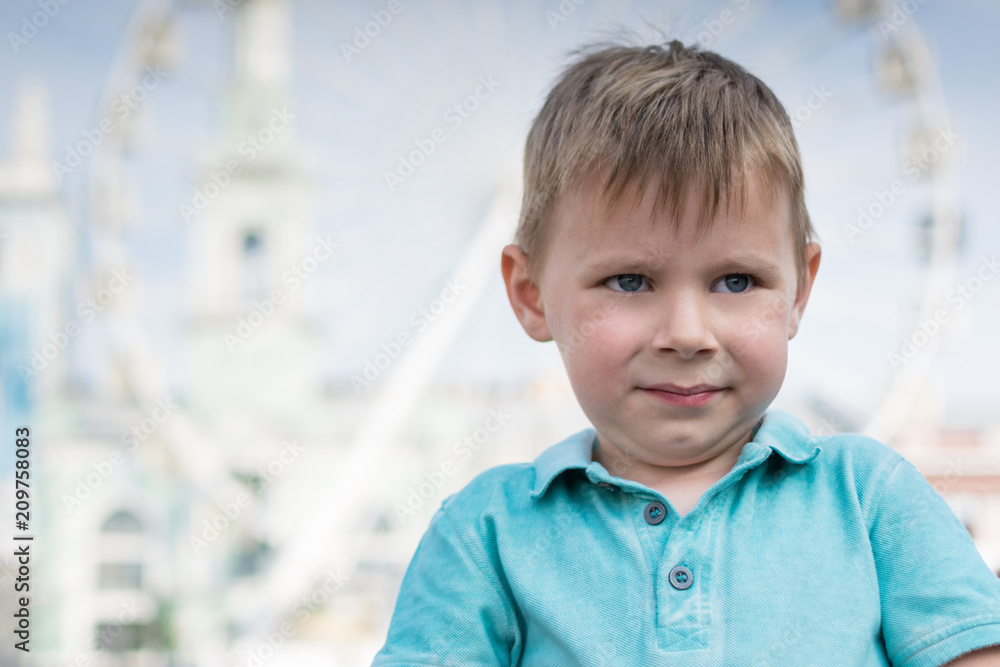 A little boy in confused emotions in the background of the Ferris wheel. A little boy in confused emotions in the background of the Ferris wheel.
