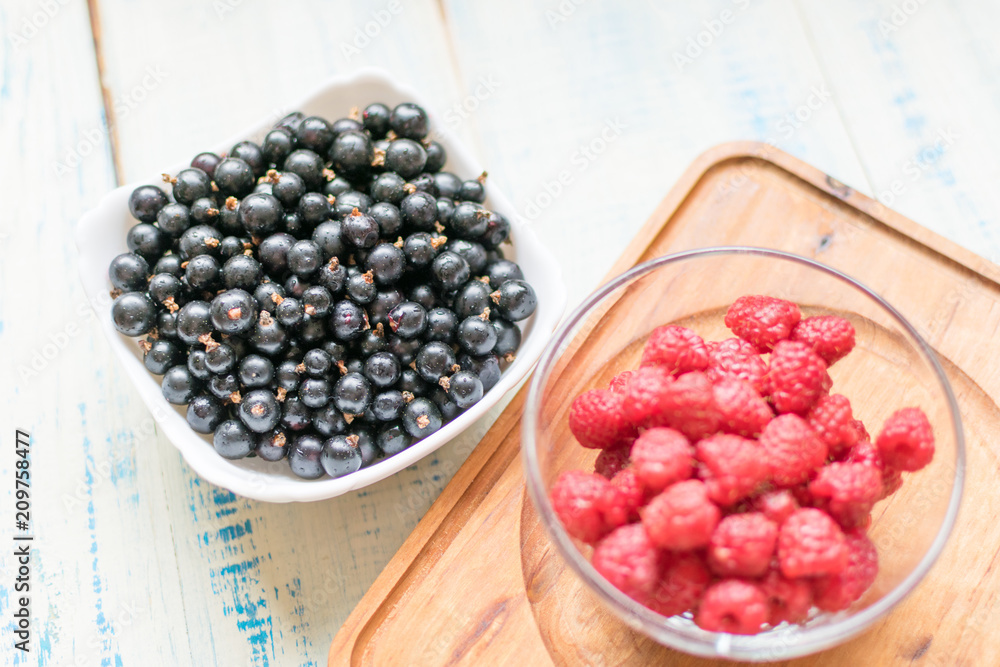 Berries of raspberries and black currants. Fresh summer berries in plates. Berries of raspberries and black currants. Fresh summer berries in plates.