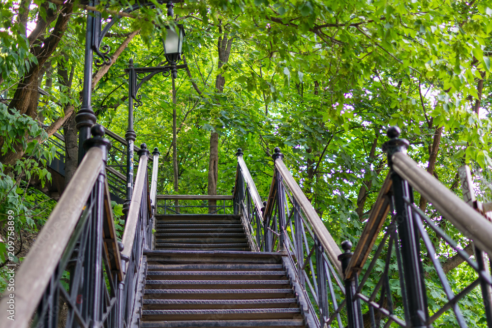 Steel staircase in the forest, surrounded by green trees. Steel staircase in the forest, surrounded by green trees.