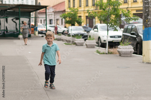 A little boy is walking along the city street.