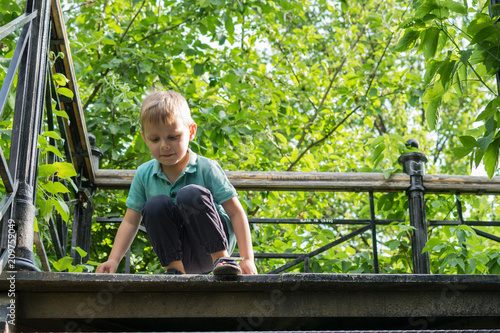 A little boy goes down the stairs in the forest.