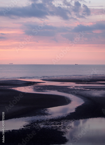 beautiful purple twilight over a calm sea with water on the beach reflecting colorful sunset clouds