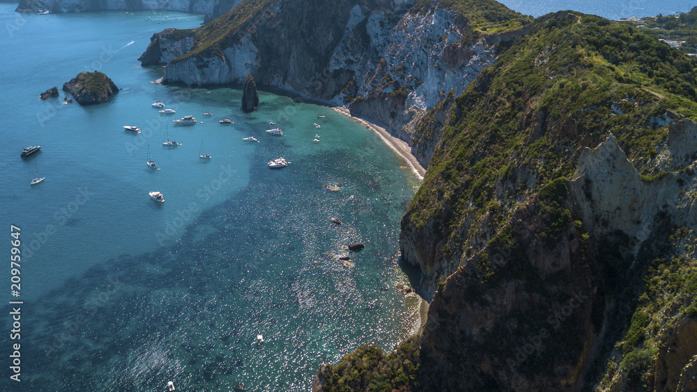 Aerial view of Frontone beach in Ponza, in Italy. This is a small bay of an island overlooking the Mediterranean Sea. The beach is full of people.
