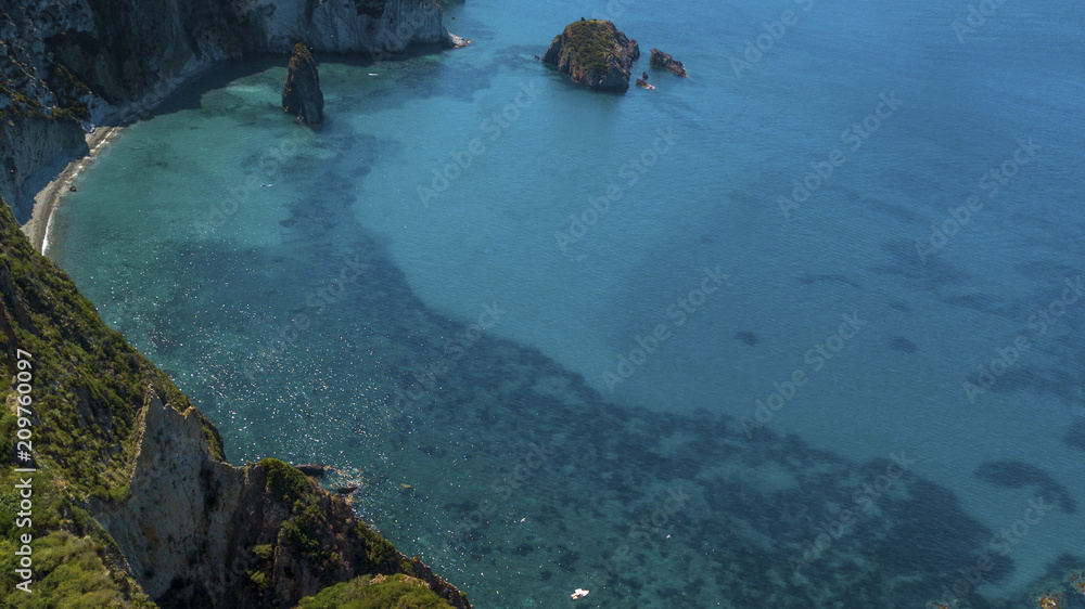 Aerial view of Frontone beach in Ponza, in Italy. This is a small bay of an island overlooking the Mediterranean Sea. The beach is full of people.