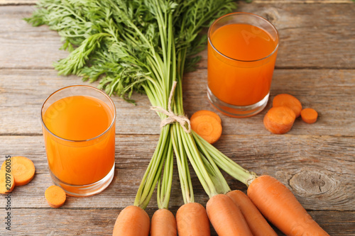 Fresh carrot juice in glasses on wooden table