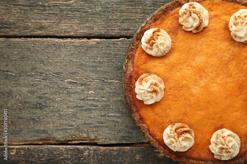Pumpkin tart with whipped cream on wooden table