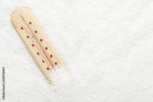 Wooden thermometer in white snow