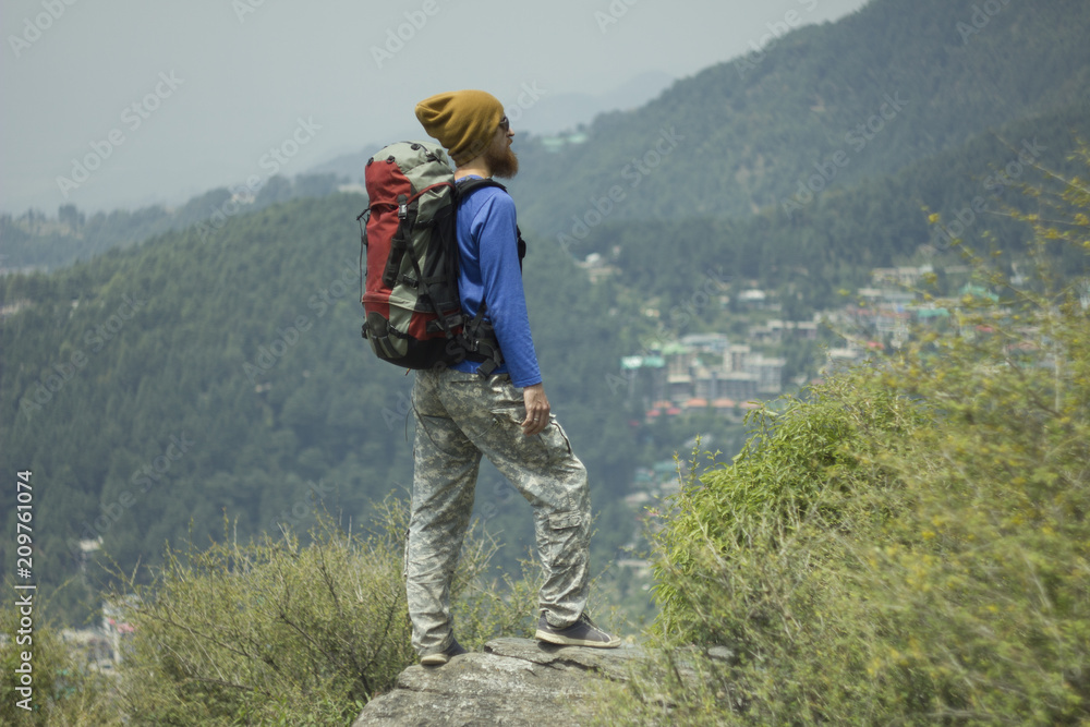 bearded man tourist trekking with backpack in valley mountains