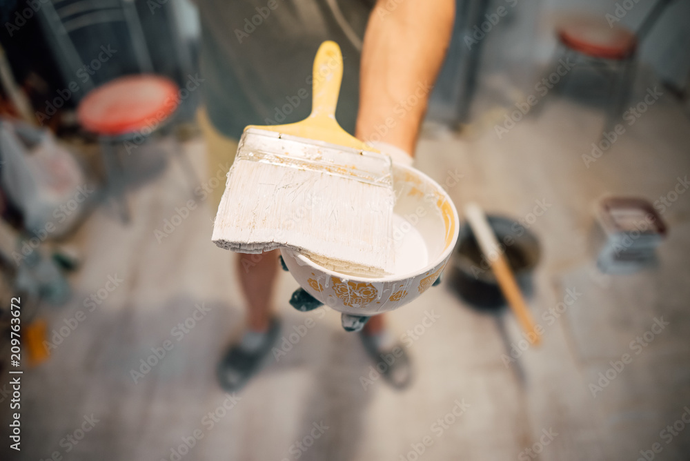A man's hand with a brush with white door paint. Selected focus A man's hand with a brush with white door paint. Selected focus
