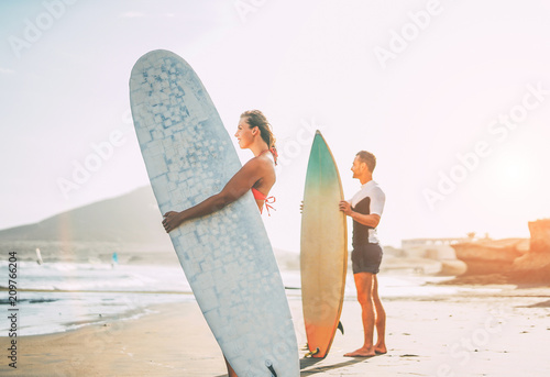 Εκτύπωση καμβά Young couple of surfers standing on the beach with surfboards preparing to surf