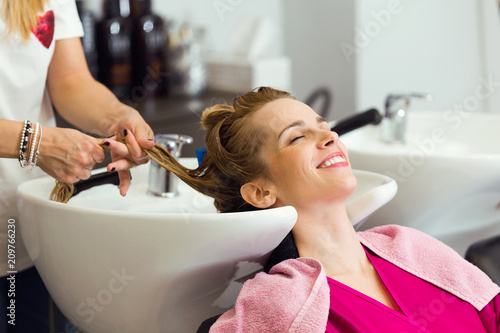 Pretty young woman washes hair in a beauty salon.