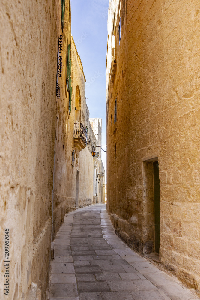 Narrow limestone street with a lantern in the distance in Mdina, Malta