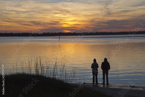 Couple Watches a Beautiful Sunset Over the Water Together