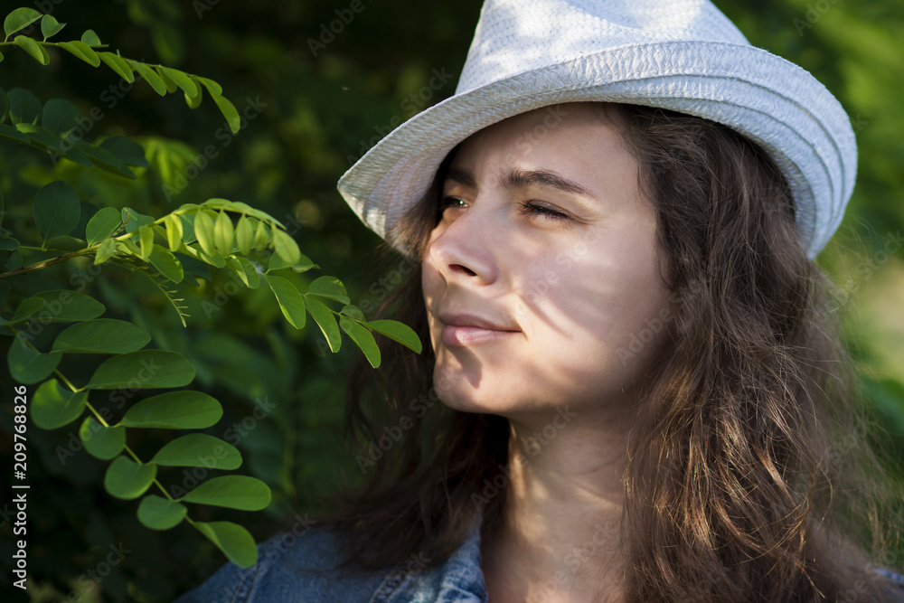 Attractive young woman in a hat looks through the branches of a tree Attractive young woman in a hat looks through the branches of a tree
