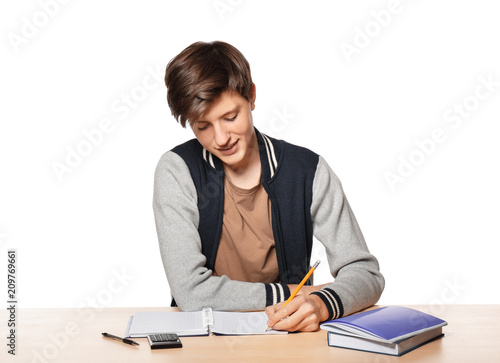Cute teenager boy doing homework against white background