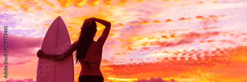 Hawaii surf summer vacation lifestyle. Silhouette of surfer woman at sunset with surfboard on beach. Banner panorama.