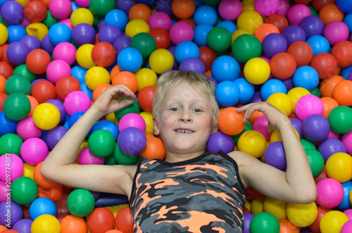 The boy lies, buried in the colorful balls of the game room.