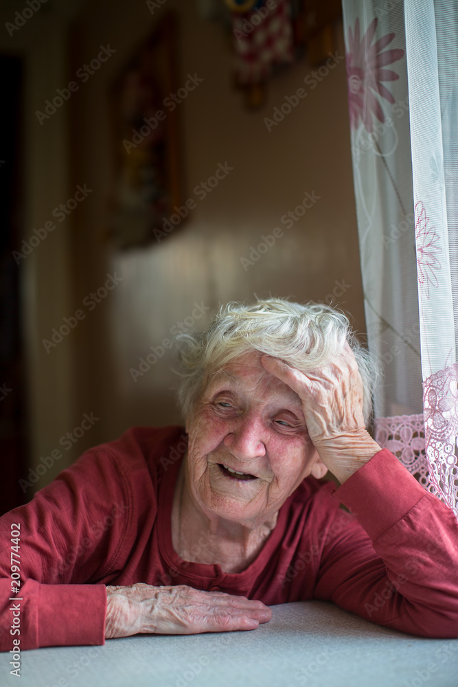 An emotional old lady is sitting at the kitchen table. An emotional old lady is sitting at the kitchen table.