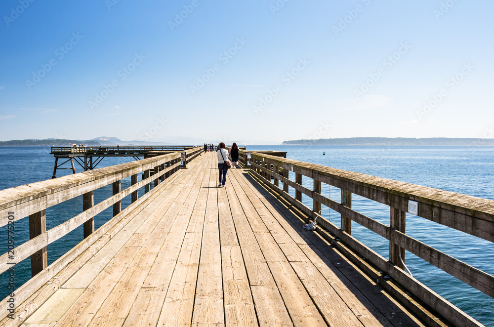 Peplo Walking on a Wooden Pier on a Clear Summer Day