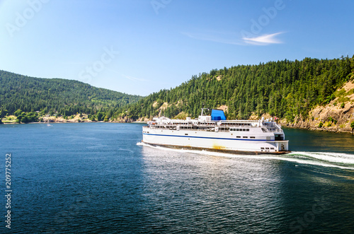 Passenger Ferry in Navigation with a Forested Island in Background on a Clear Summer Day