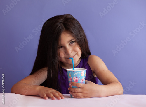 Cute little brunette girl drinking fresh juice