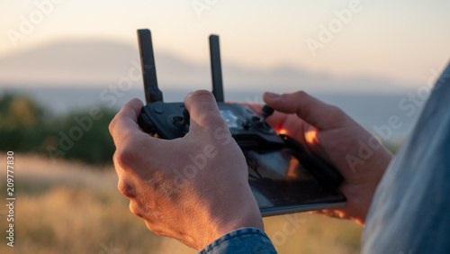 hands holding drone controller in sunset