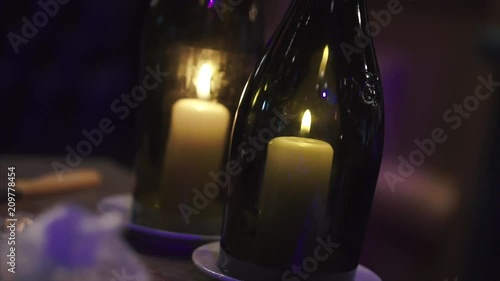 A candle burns in the bottles. Clip. Summer homemade decoration, glass jar and bottle, led candle flame light inside photo