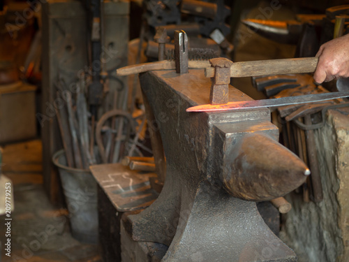 Man smithing a red-hot piece of metal on an anvil