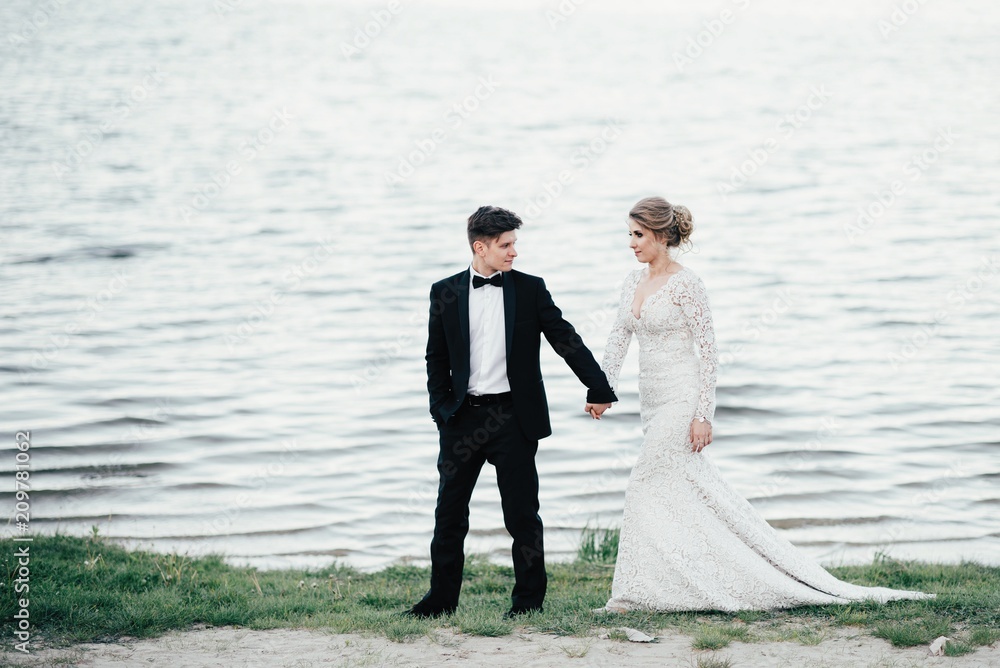 Wedding. The young cute couple walks and spends time at the local beach near the lake Wedding. The young cute couple walks and spends time at the local beach near the lake