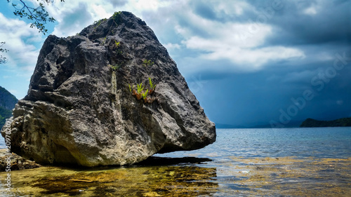 Giant rock standing above ocean on a stormy day