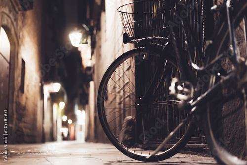 retro bicycle in the night old city on background bokeh light flare in night architecture, vintage bike in evening street in barcelona town, cycle transportation in backdrop building, travel concept © A_B_C