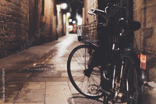 retro bicycle in the night old city on background bokeh light flare in night architecture, vintage bike in evening street in barcelona town, cycle transportation in defocus backdrop, travel concept © A_B_C