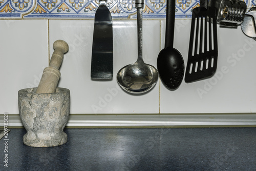 close-up hung kitchenware and a stone mortar with a tile background