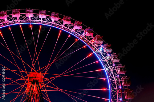 Big ferris wheel with festive red and purple illumination